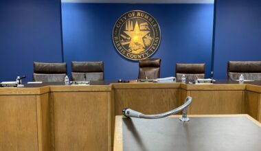 a city council meeting room with black chairs and blue walls