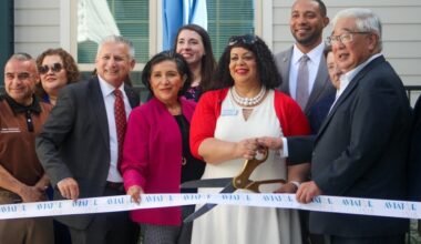 people in formal attire cut a ribbon with large scissors