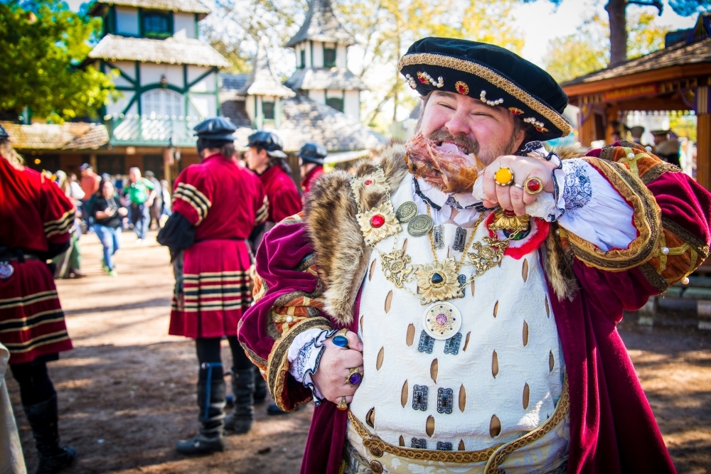 Renaissance faire performers with a king eating a turkey leg