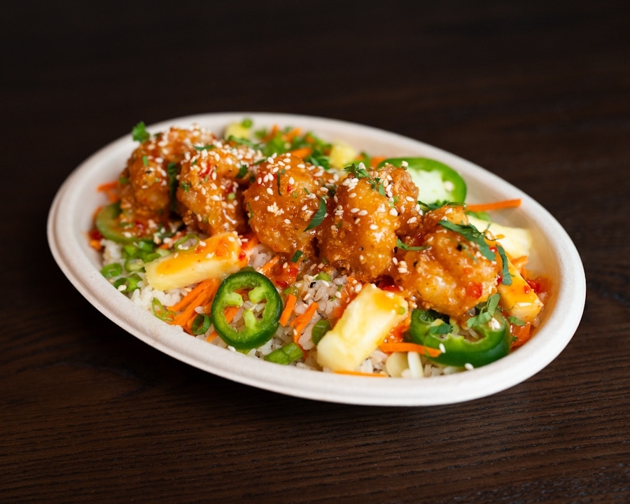 Overview of a bowl filled with meat, jalapeno slices, rice, seasonings and more.