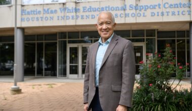 a man in a gray blazer stands in front of an education building
