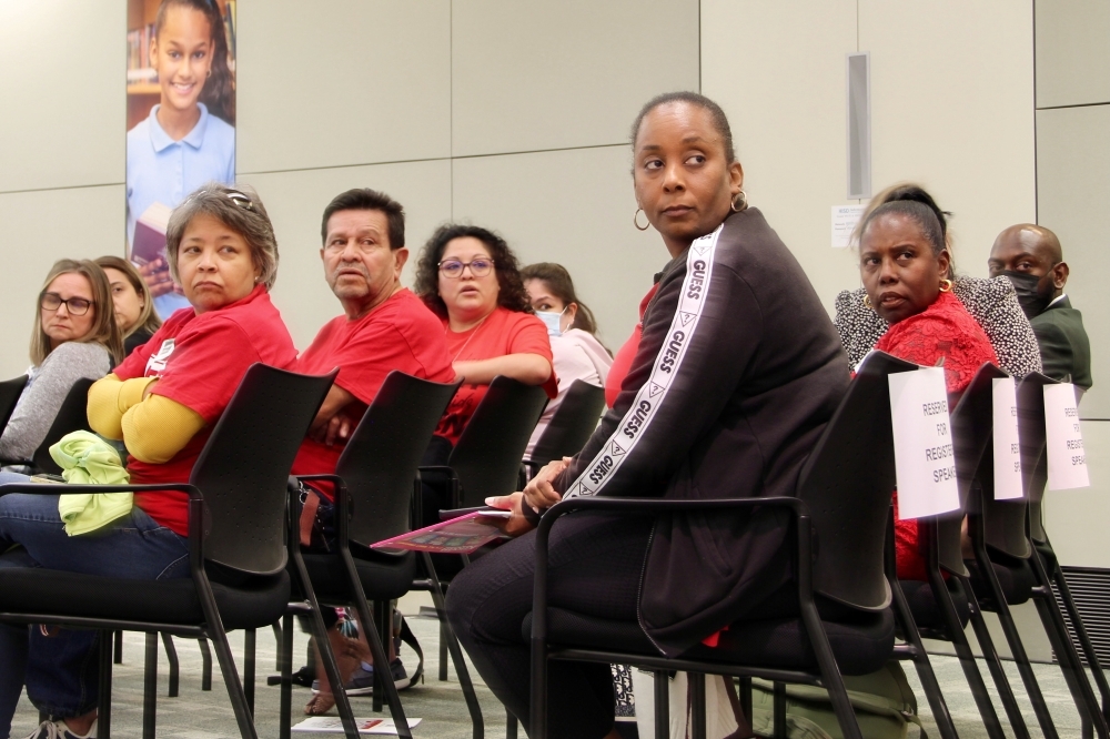 people sit in chairs in a row and look over their shoulders at something out of the frame
