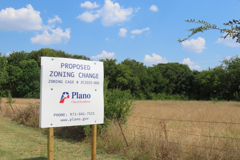 a white sign surrounded by trees and green landscape