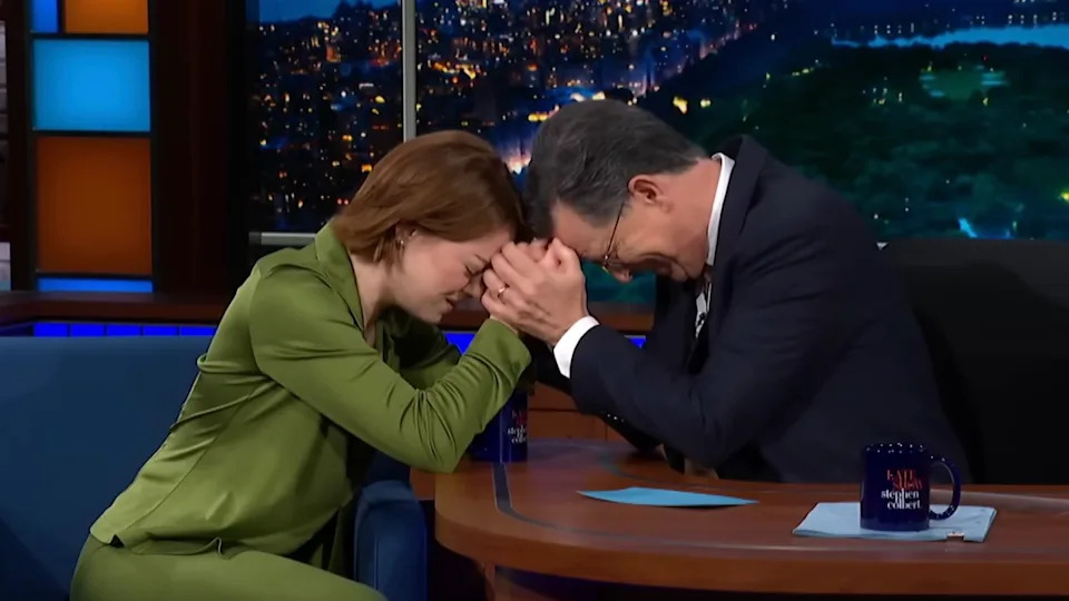 Emma Stone clasping hands with Stephen Colbert on The Late Show with Stephen Colbert