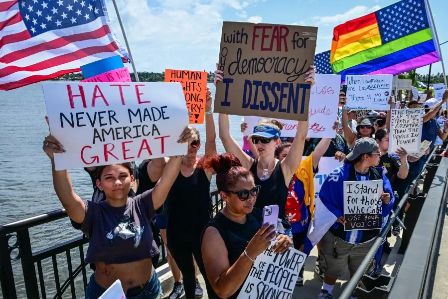 Demonstrators holding signs and flags, protest the Trump administration during the “No Kings” rally near US President Donald Trump’s Mar-a-Lago home in West Palm Beach, Florida, on June 14, 2025, on the same day as President Trump’s military parade in Washington, DC. In response to the military parade celebrating the 250th anniversary of the US Army but also coinciding with Trump’s 79th birthday, a “No Kings” movement has sprung up promising to stage protests in more than 2,000 places across the country, including a large parade expected in Los Angeles which organizers say will feature a “20-foot-tall balloon of Trump wearing a diaper.” (Photo by Giorgio Viera / AFP) (Photo by GIORGIO VIERA/AFP via Getty Images)