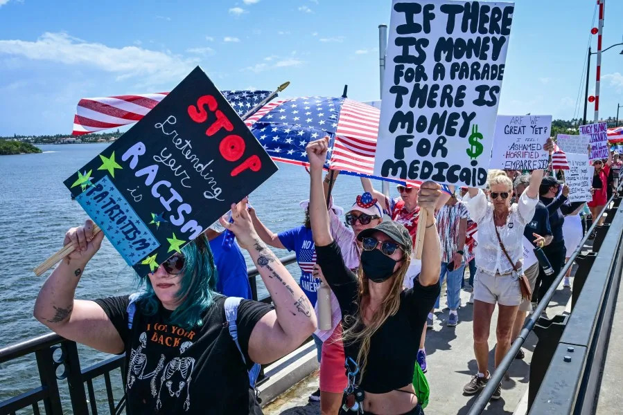Demonstrators protest the Trump administration during the “No Kings” rally near US President Donald Trump’s Mar-a-Lago home in West Palm Beach, Florida, on June 14, 2025, on the same day as President Trump’s military parade in Washington, DC. In response to the military parade celebrating the 250th anniversary of the US Army but also coinciding with Trump’s 79th birthday, a “No Kings” movement has sprung up promising to stage protests in more than 2,000 places across the country, including a large parade expected in Los Angeles which organizers say will feature a “20-foot-tall balloon of Trump wearing a diaper.” (Photo by Giorgio Viera / AFP) (Photo by GIORGIO VIERA/AFP via Getty Images)