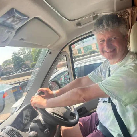 Alan Smith Alan Smith smiles as he sits in the driver's seat of his caravan.