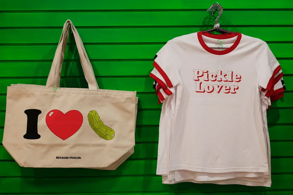 A pickle-themed tote and t-shirt sit on display to be sold at The Pickle Factory, Wednesday, Oct. 8, 2025, in Jacksonville, Fla. The retail outlet that sells all things pickle, has expanded an additional 1,500 square feet of space.