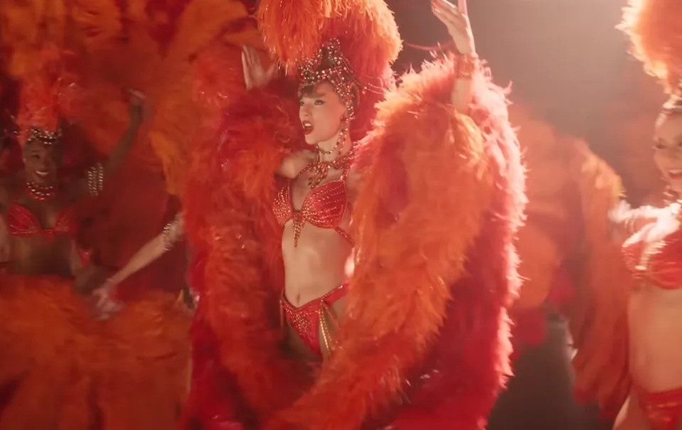 Person in a showgirl outfit with feathered headdress and elaborate costume, dancing on stage