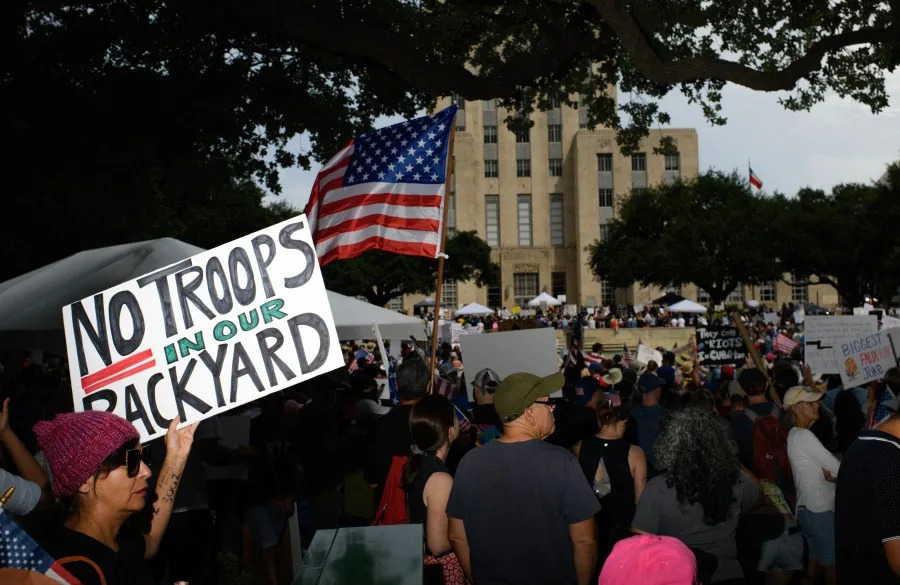 A person holds up a sign reading “No Troops in our Backyard” during the “No Kings” protest in downtown Houston, Texas, June 14, 2025, on the same day as President Trump’s military parade in Washington, DC. In response to the military parade celebrating the 250th anniversary of the US Army but also coinciding with Trump’s 79th birthday, a “No Kings” movement has sprung up promising to stage protests in more than 2,000 places across the country, including a large parade expected in Los Angeles which organizers say will feature a “20-foot-tall balloon of Trump wearing a diaper.” (Photo by Mark Felix / AFP) (Photo by MARK FELIX/AFP via Getty Images)