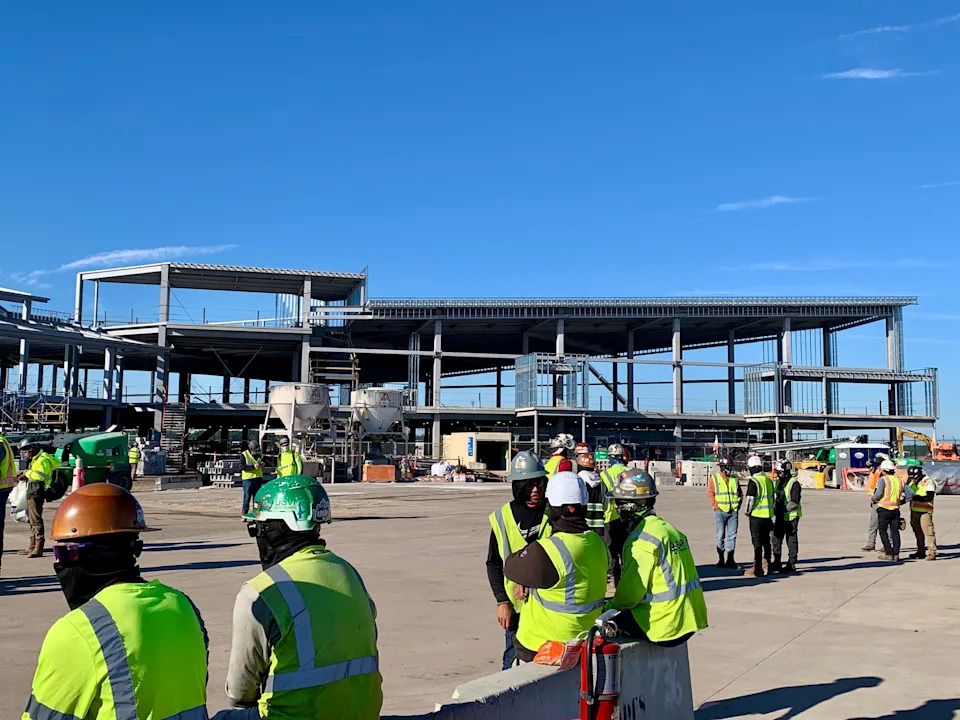 Construction workers await the topping off ceremony at Jacksonville International Airport on Oct. 24, 2025 marking a milestone for installing the last piece of steel for the structure of the new concourse being built at the airport.
