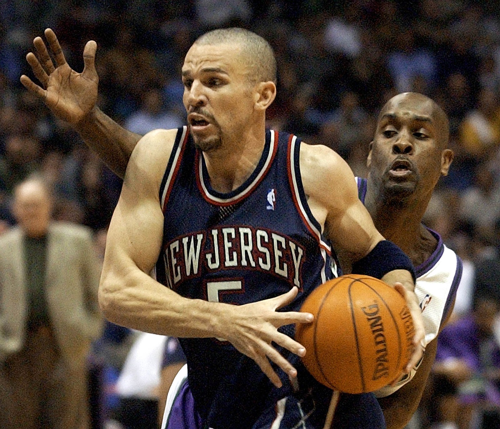 Two basketball players, one of them (Jason Kidd) in the foreground with the ball, the other (Gary Payton) playing defense behind him.