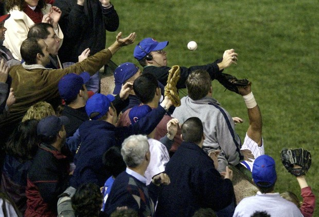 FILE - In this Oct. 14, 2003, file photo, Chicago Cubs left fielder Moises Alou's arm is seen reaching into the stands, at right, unsuccessfully for a foul ball along with a fan Steve Bartman during Game 6 of the National League Championship Series against the Florida Marlins in Chicago. The Cubs went on to lose the series. As the Cubs take on the Mets in the hopes of getting to the 2015 World Series for the first time since 1945 and winning it for the first time since 1908, Cubs fans swear that this team will win, because of the way they play and not because a curse was lifted. (AP Photo/Morry Gash, File)