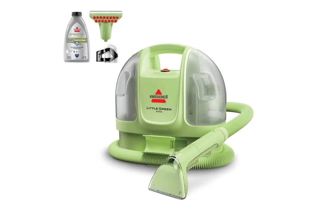 The Bissell Little Green Mini with a bottle of cleaning solution and accessories near by.
