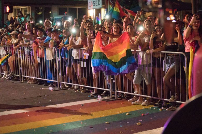 The largest mass of people is centralized next to the new rainbow crosswalk at the intersection of Main and Evergreen streets.