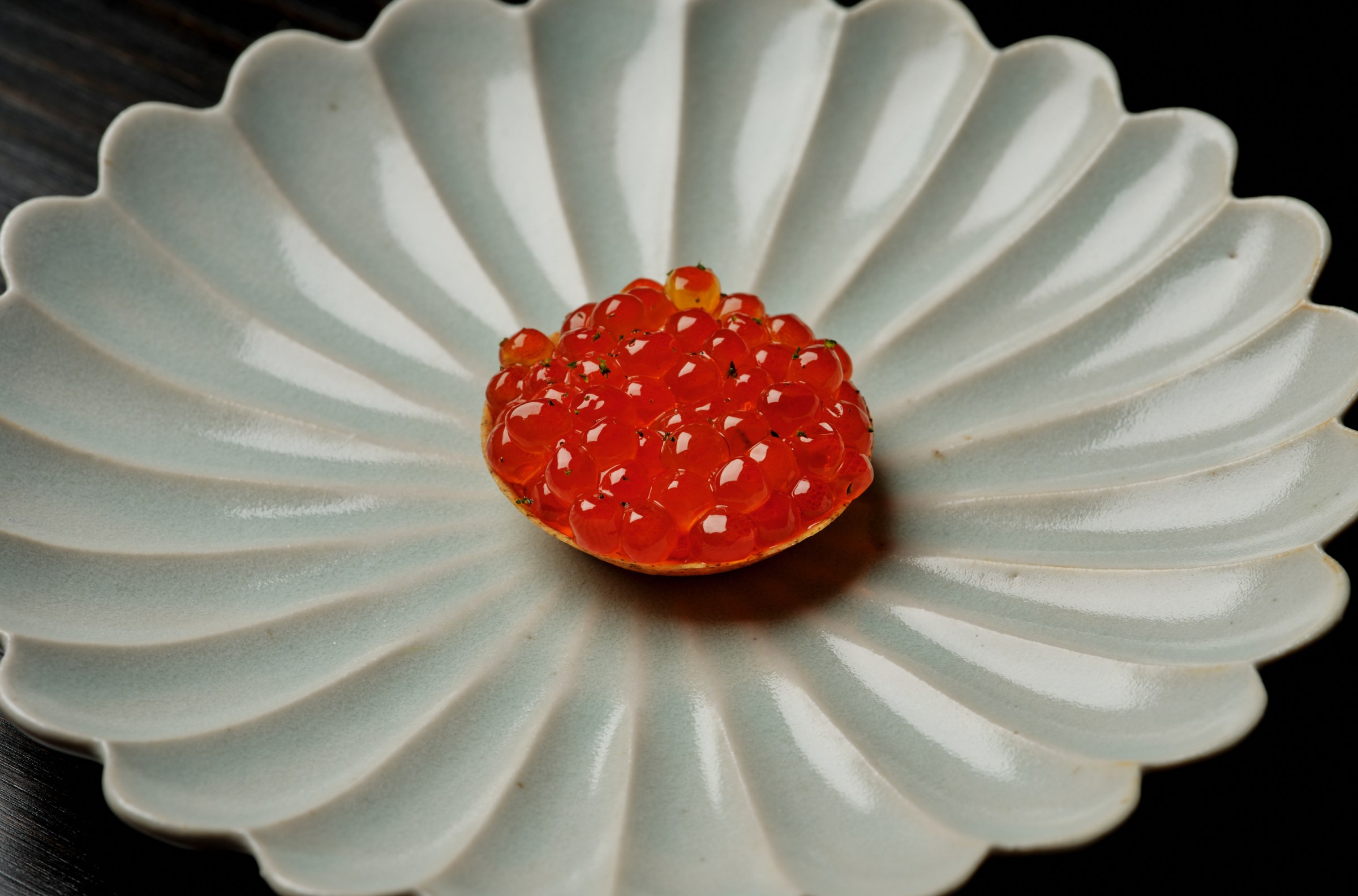 Tart topped with orange ikura on a decorative platter