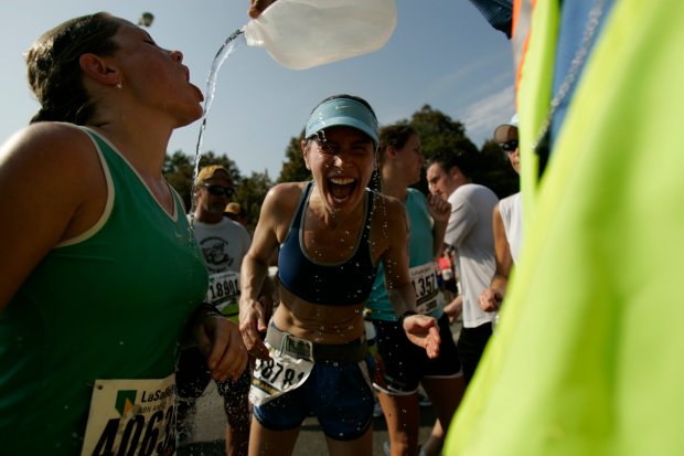 Amber Mercier, left, and Leslee Hewlett, both of Chicago, receive water as the runners head east on West Jackson Boulevard at the marathon on Oct. 7, 2007. The race was cut short due to heat-related stresses, and one person died during the event. (José M. Osorio/Chicago Tribune)