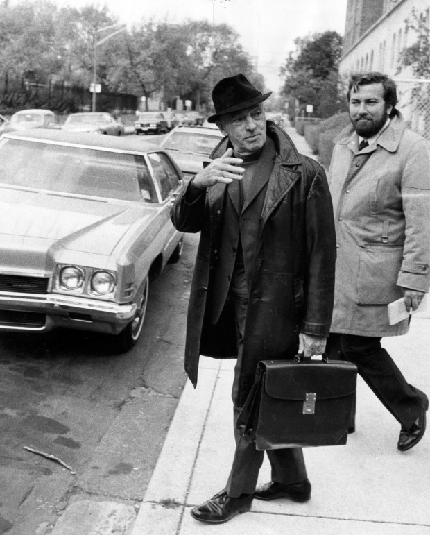 Author Saul Bellow, center, leaves his home on Oct. 21, 1976, in Chicago. Bellow had won the Nobel Prize. (George Quinn/Chicago Tribune)