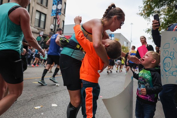 Ashley Golen stops to hug her sons Max, 5, and Charlie, 3, as she runs on Halsted Street in Greektown during the Chicago Marathon on Oct. 13, 2024. (Eileen T. Meslar/Chicago Tribune)