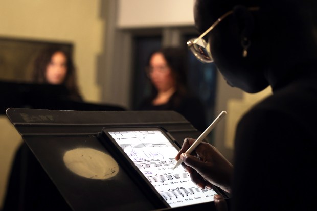 Nyandeng Juag takes notes during a rehearsal of La Caccina's fall concert, Oct. 6, 2025, at Our Lady of Mount Carmel Church in Chicago. (Anastasia Busby/for the Chicago Tribune)