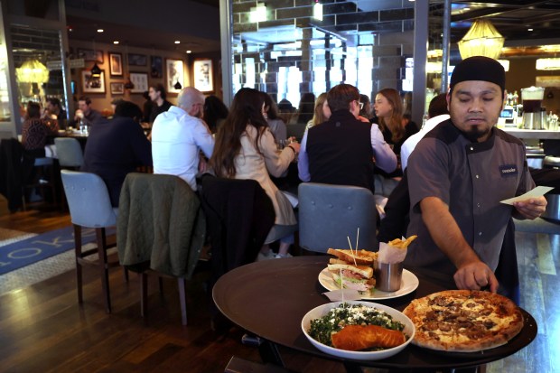A server delivers meals for diners at The Roanoke restaurant in Chicago, Oct. 21, 2025. (Antonio Perez/Chicago Tribune)