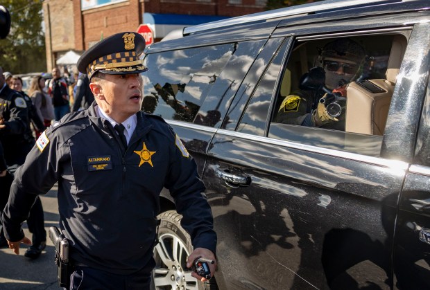 A U.S. Customs and Border Patrol officer points a crowd control weapon out the window of a vehicle at protesters while Chicago police Cmdr. Lazaro Altamirano walks past as police clear the crowd for their exit on Oct. 23, 2025, after a raid at Discount Mall on West 26th Street in Little Village. (Brian Cassella/Chicago Tribune)