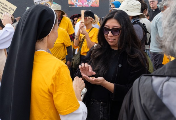 Dominican Sister Christin Tomy, left, serves communion to members of a procession outside of the Immigration and Customs Enforcement processing facility in Broadview after eucharistic ministers, including Tomy, attempted to serve Holy Communion to detainees, Oct. 11, 2025, during the Coalition for Spiritual and Public Leadership's eucharistic procession. The procession marched from St. Eulalia Catholic Church in Maywood. (Dominic Di Palermo/Chicago Tribune)