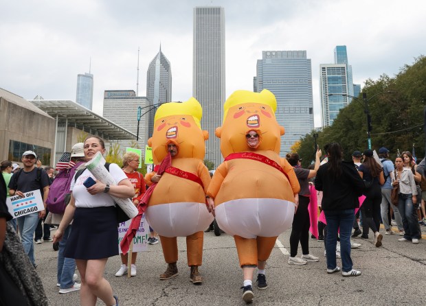 Demonstrators wearing inflatable Donald Trump costumes walk on Columbus Avenue during the "No Kings" rally at Butler Field Saturday, Oct. 18, 2025, in Chicago. (John J. Kim/Chicago Tribune)