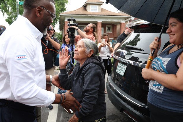 Mayor Brandon Johnson gives a hug to Aguirre Matilde as he tours a flood affected area and talks with residents following two days of heavy rain in the 5700 block of South Campbell in Chicago on Aug. 19, 2025. (Antonio Perez/Chicago Tribune)