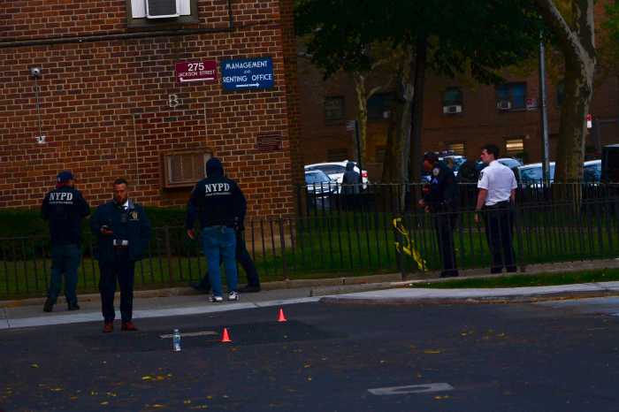 Detectives work inside the cordoned-off parking lot of a NYCHA complex