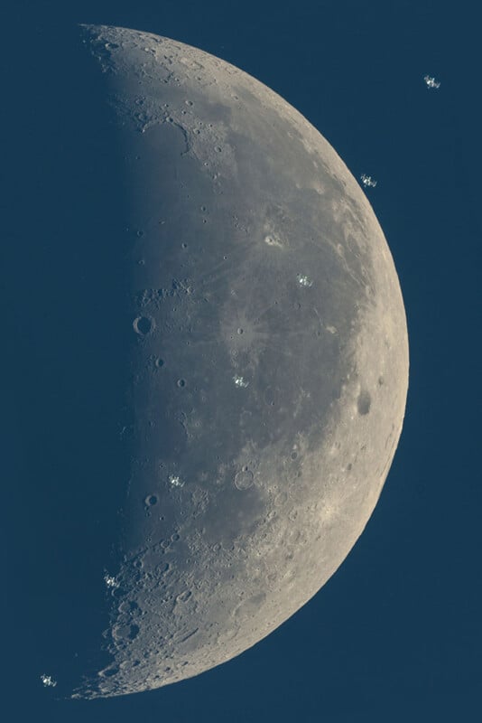 A close-up photo of the moon in its first quarter phase, showing detailed craters and lunar surface textures, with multiple tiny silhouettes of the International Space Station passing across it.