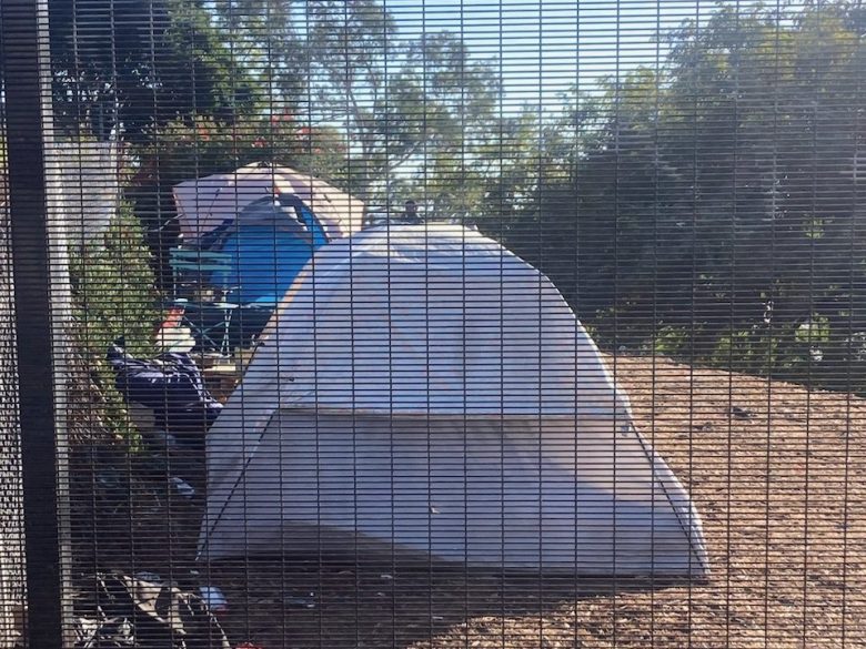 Tents errcted behind a fence.