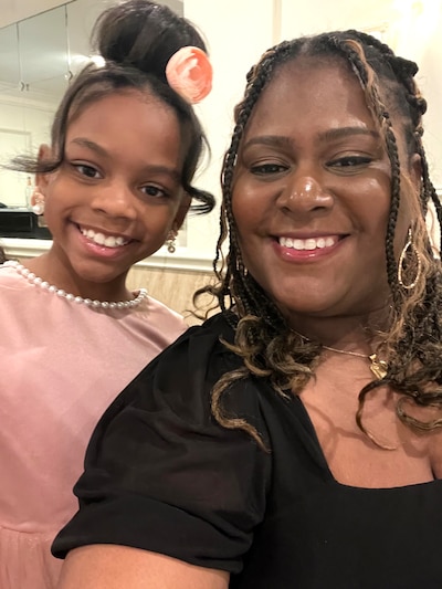 A portrait of a young girl and her mother in a black top.