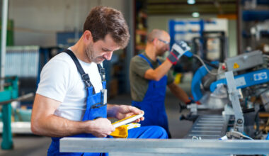 man looking at a metal piece in a workshop
