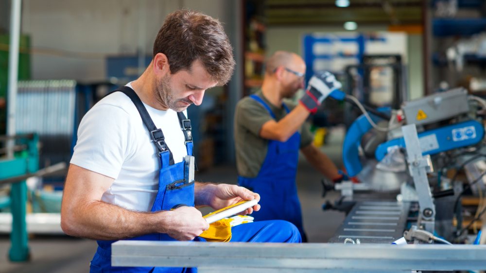 man looking at a metal piece in a workshop