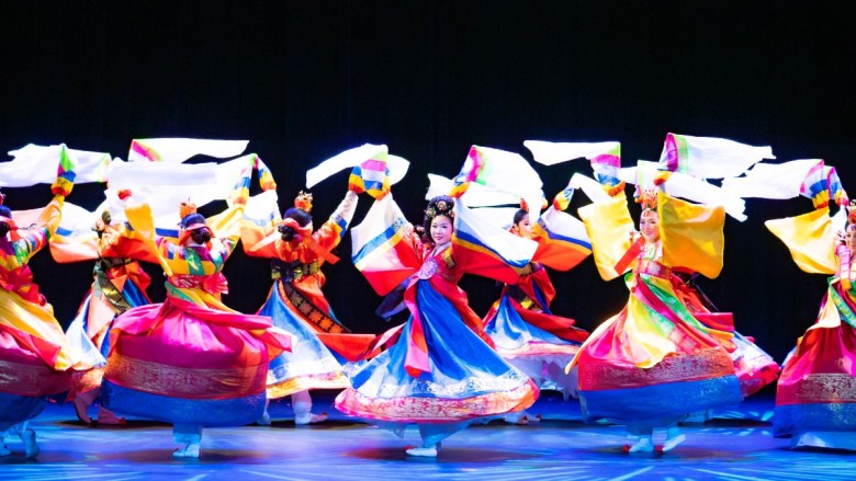Traditional Korean dancers in colorful hanbok performing with white cloths on stage.