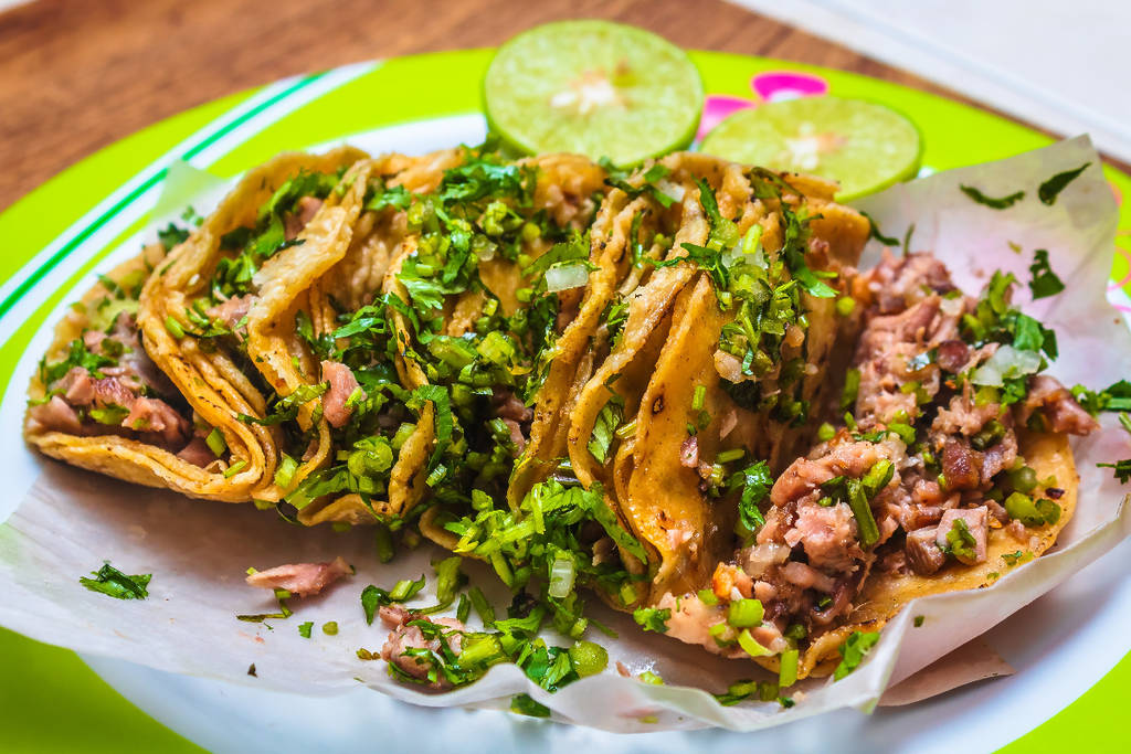 Image shows a tray of tacos with cilantro on top.