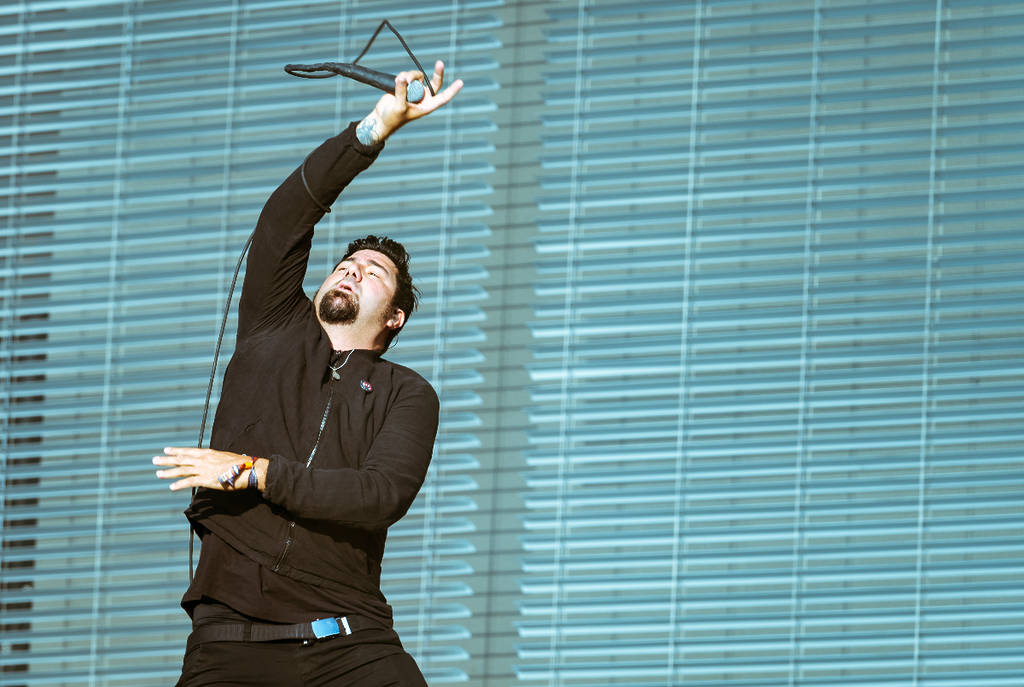 Image shows Deftones frontman Chino Moreno performing on stage at a concert.