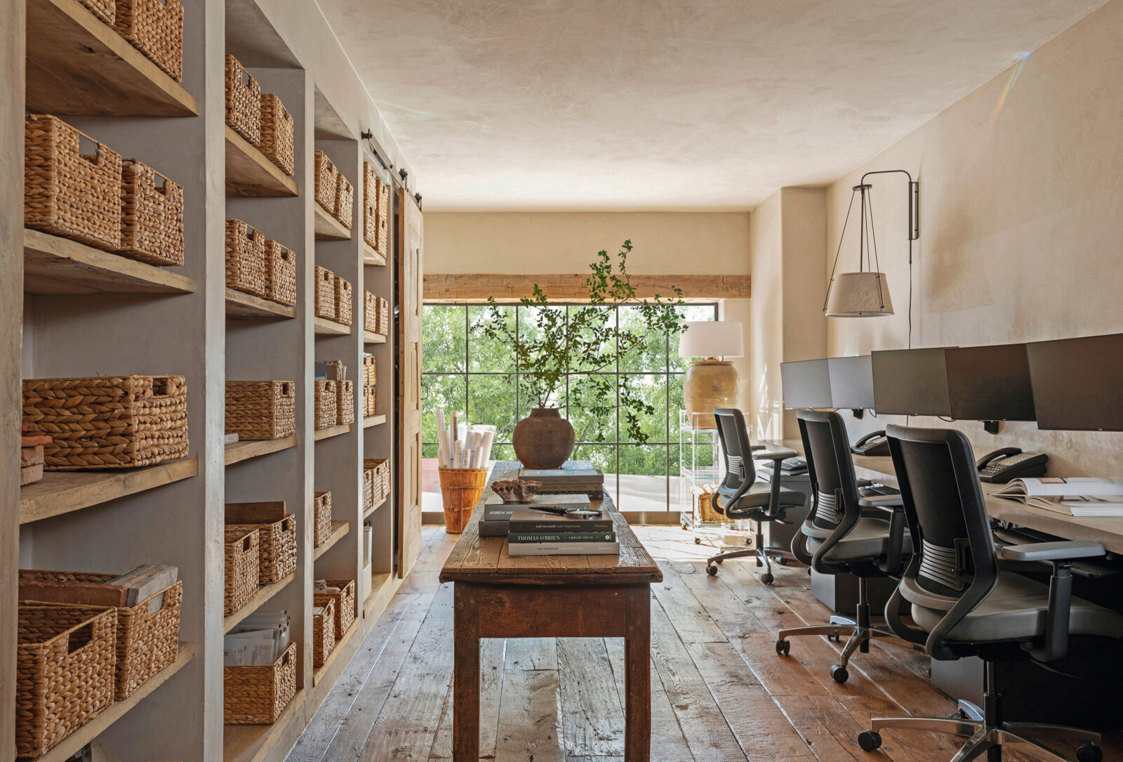 A home office with wood floors and walls of wicker shelving