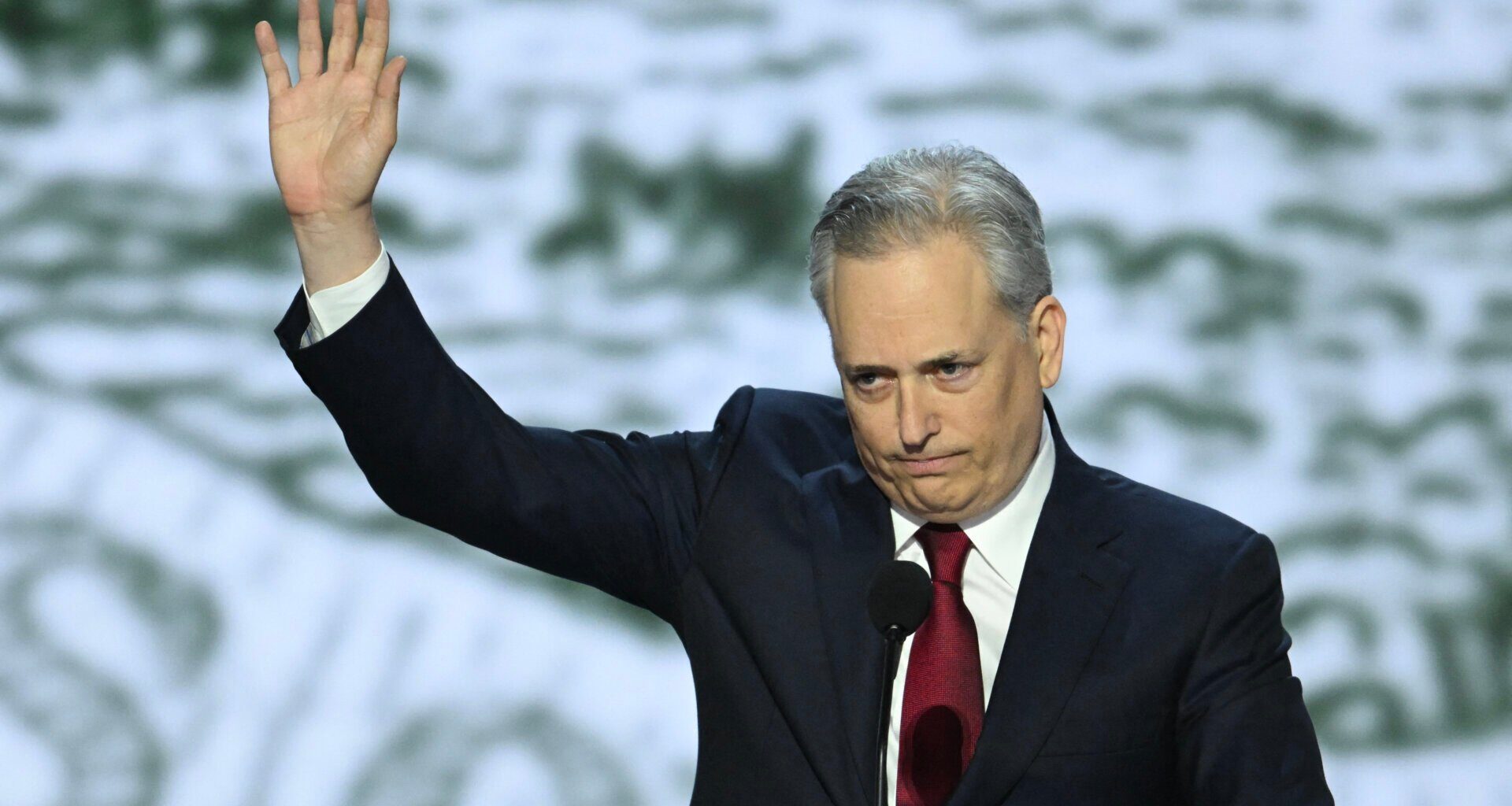 David Sacks pictured in front of a microphone, waiving to the crowd