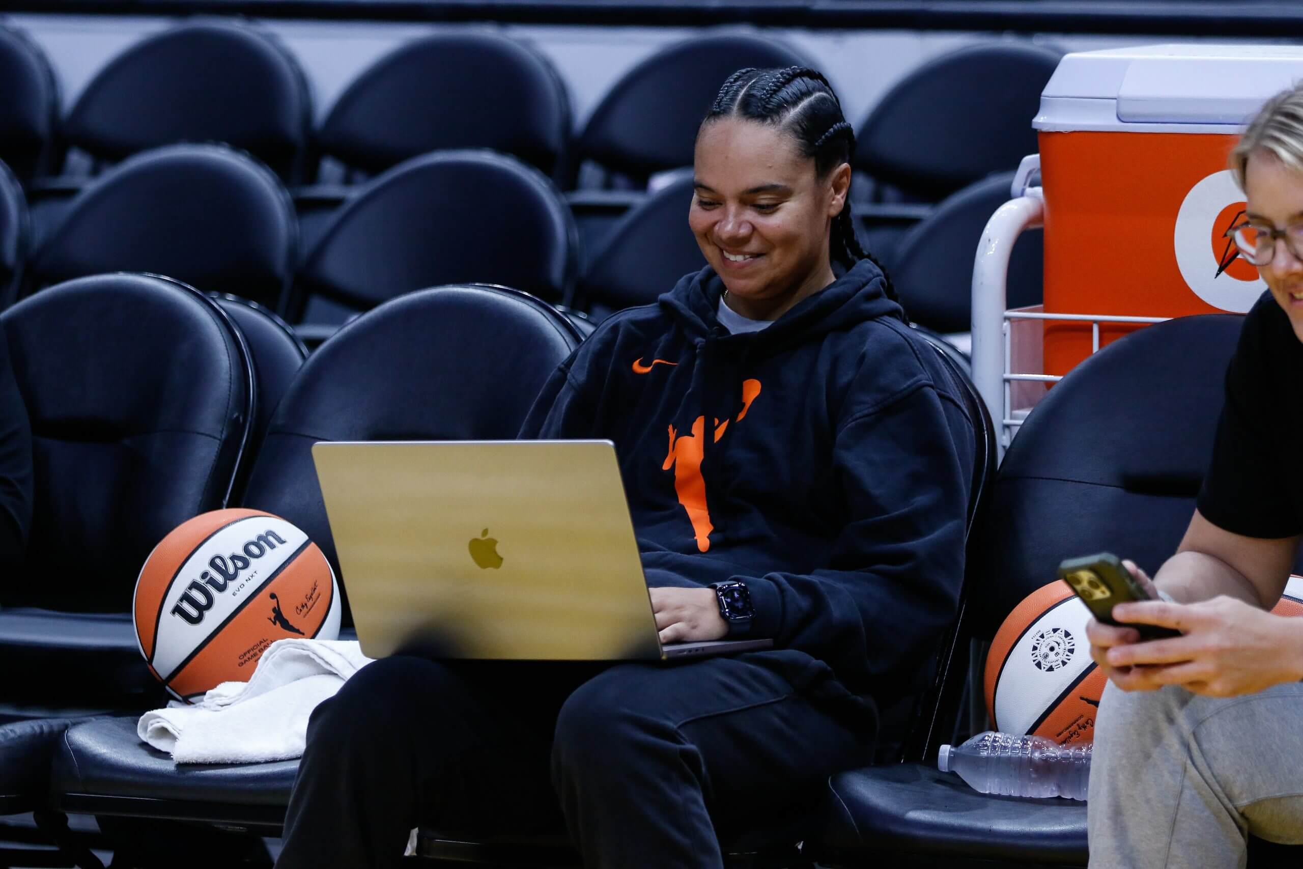 Mercury assistant Kristi Toliver sits on the sideline using her laptop.