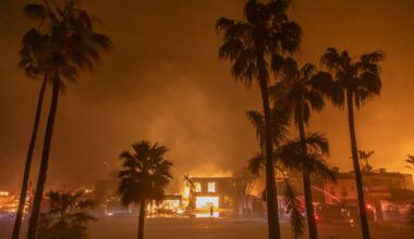 A firefighter watches the flames from the Palisades Fire burning homes on the Pacific Coast Highway amid a powerful windstorm on January 8, 2025 in Los Angeles, California.
