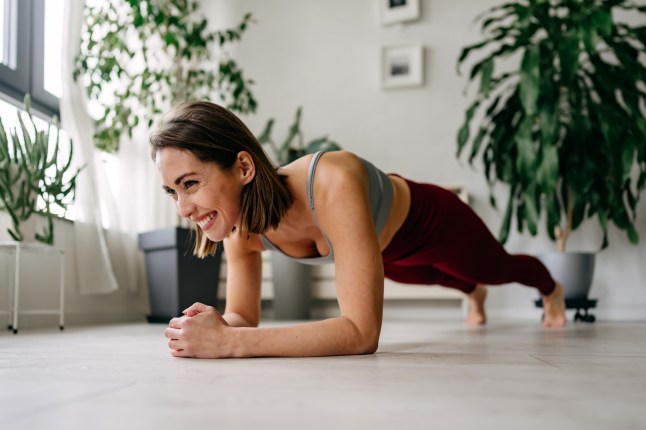 Smiling woman doing plank exercise at home