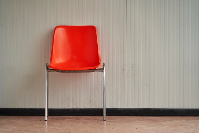 Lonely orange plastic chair standing in an empty waiting room
