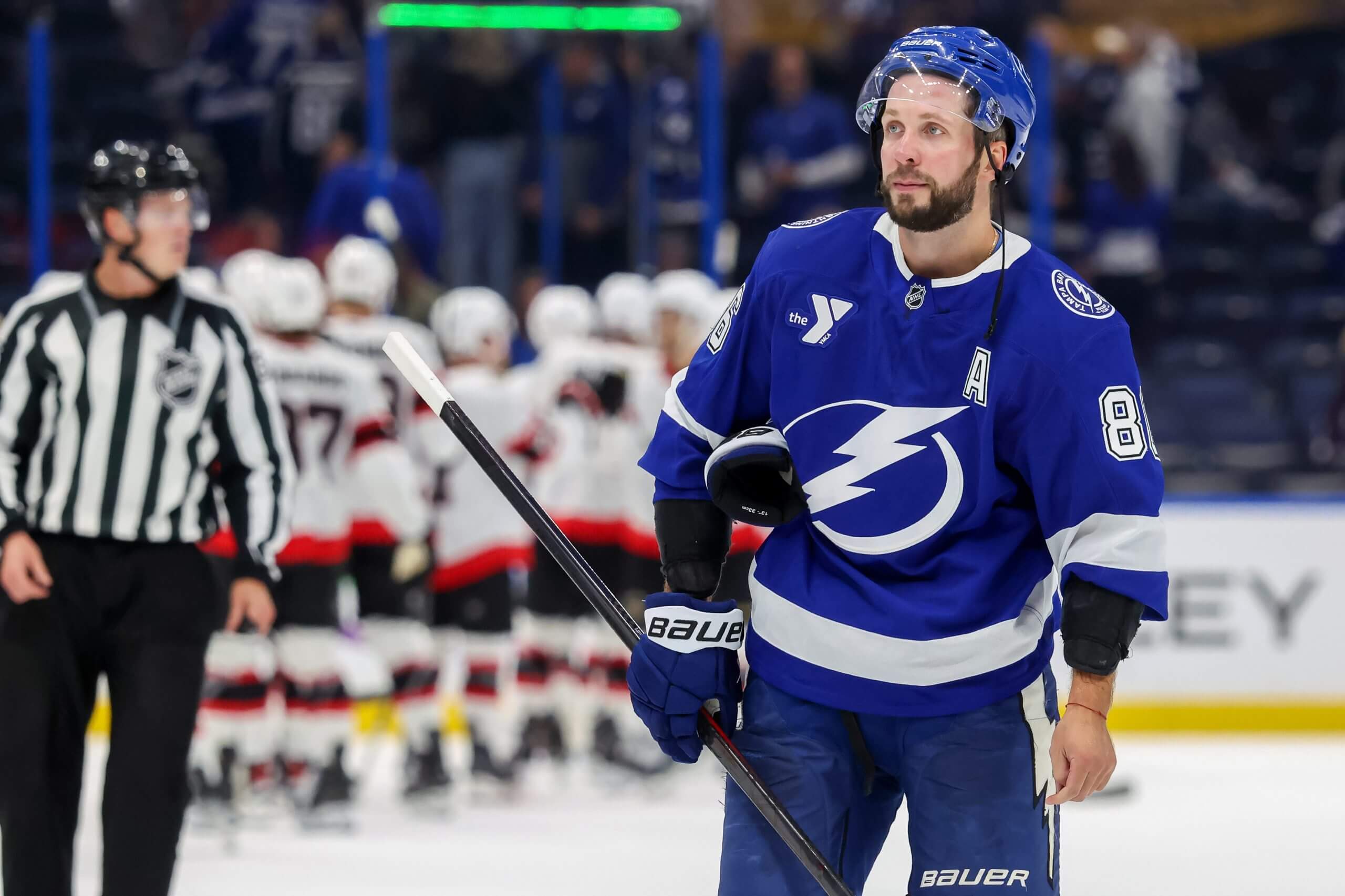 Nikita Kucherov looks into the distance with celebrating Senators players behind him.