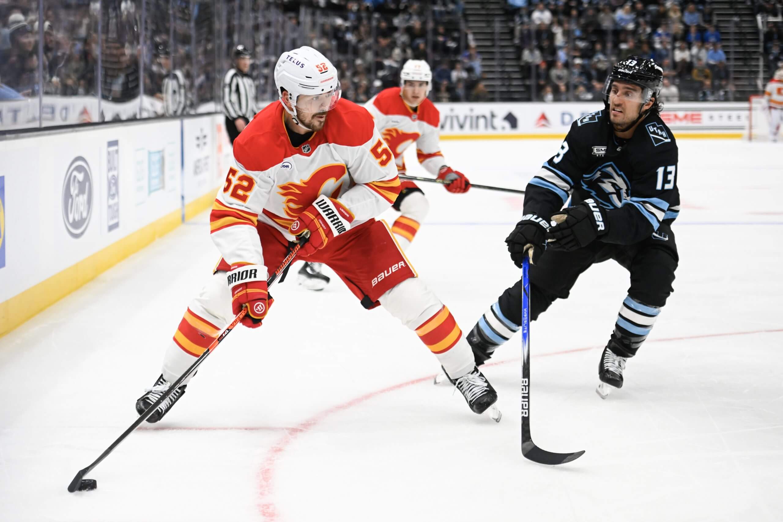 MacKenzie Weegar looks for a pass while keeping the puck away from Utah's Brandon Tanev.