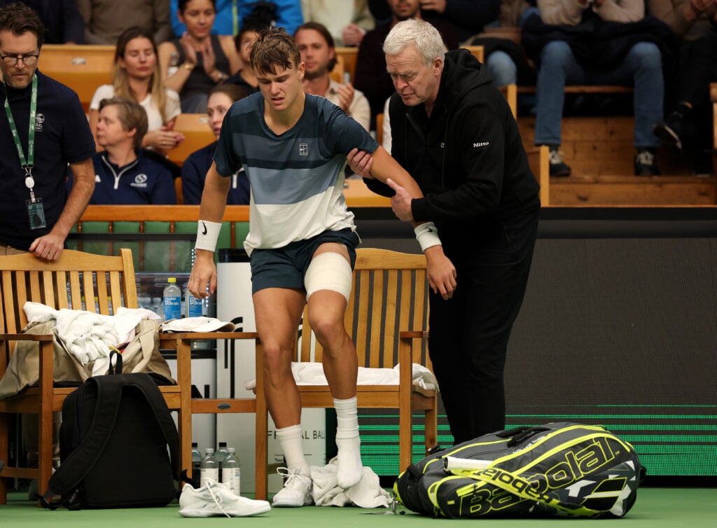Holger Rune of Denmark is assisted off the court as he is forced to retire following an injury against Ugo Humbert of France during the Men's Singles semi-final match on day eight of the BNP Paribas Nordic Open 2025 at Royal Tennis Hall.