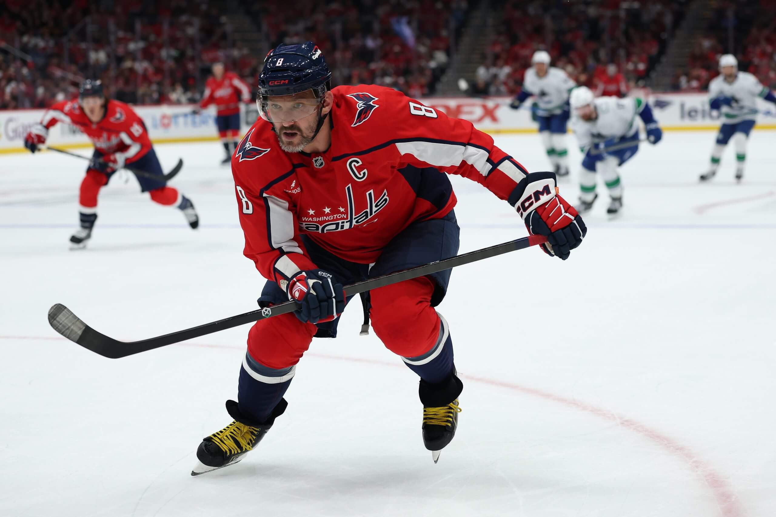 Alex Ovechkin skates up the ice with Capitals and Canucks players behind him.