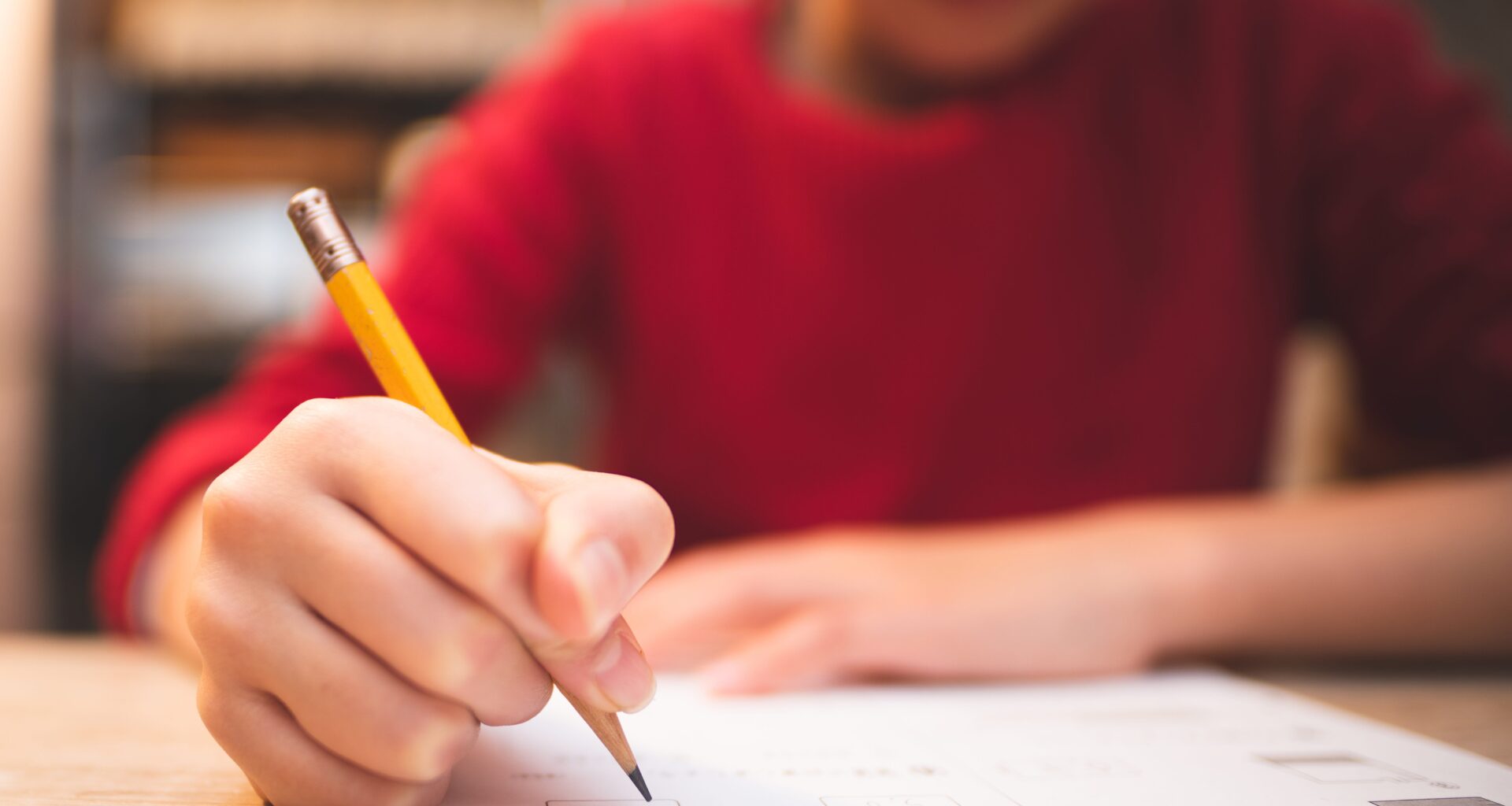 A child writes at his desk in class.