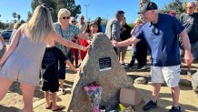 Family and friends took a moment to touch the new granite memorial in a sign of support, after Saturday's memorial ceremony, Ocean Beach, Calif., October 11, 2025.